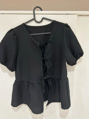 Svart peplumtopp - Svart peplumtopp med knytning framtill. Använd 1 gång