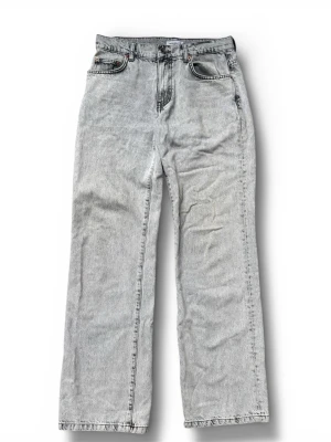 Woodbird snow jeans - Säljer ett par ljusgråa jeans med rak passform och klassisk femficksdesign. Jeansen har hög midja och är tillverkade i denim med en tvättad look. Perfekta för en avslappnad och trendig stil.