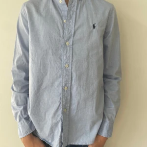 Ljusblå skjorta från Polo Ralph Lauren - Snygg ljusblå skjorta från Polo Ralph Lauren i slimfit. Är i mycket fint skick och har inga skador. Stl 16 Nypriss är 1200kr hör av er vid frågor