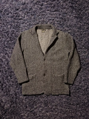 Massimo Dutti kavaj - Stilren grå kavaj i klassiskt fiskbensmönster. Kavajen har två knappar framtill, två fickor och en mjuk, stickad känsla. Perfekt för dig som gillar en avslappnad men ändå dressad look. Materialet känns tjockt och passar bra till kyligare dagar. Hör av er vid minsta fundering! Passar S-XS