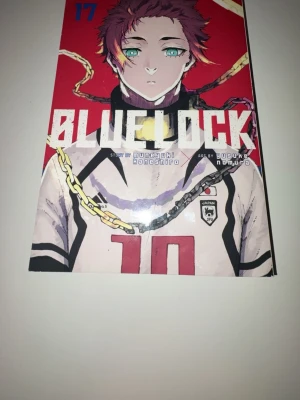 Blue Lock volym 17 manga - Blue Lock volym 17 är en japansk manga med färgstark röd och vit framsida, tecknad av Yusuke Nomura och skriven av Muneyuki Kaneshiro. Boken är i pocketformat med mjuka pärmar och svartvita sidor. Perfekt för dig som gillar sport, fotboll och spännande berättelser. Lite bara lite riven men påverkar inte något
