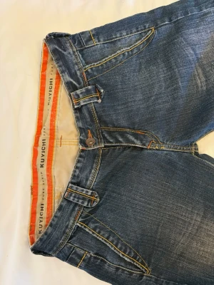 Blå jeans från Kuyichi med orange sömmar - Innerben: 84                                       midja: 39                                                   ett par klassiska blå jeans från Kuyichi med snygga orange kontrastsömmar och unika fickdetaljer. Jeansen har normal midja, bootcut ben och är tillverkade i slitstarkt denim. Perfekta för dig som gillar en avslappnad men ändå stilren look. OBS har ett hål vid höger häl då dem är lite långa på mig i överigt super bra skick 