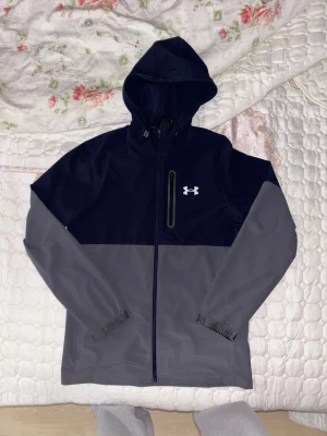 Blå och grå vindjacka från Under Armour - UA jacka som är i riktigt bra skick nästan ny men använd. Nypris 1,250, säljs inte längre. Tveka inte om att fråga om något!