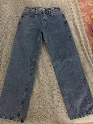 Blå raka jeans  - Klassiska blå jeans med rak passform och fem fickor. Jeansen har hög midja, bälteshällor och stängs med dragkedja och knapp. Tillverkade i slitstark denim som ger en tidlös look.