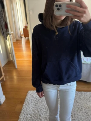 Mörkblå hoodie  - En basic mörkblå hoodie med stor huva och känguruficka framtill. Hoodien har en avslappnad passform och ribbade muddar vid ärmslut och nederkant. Perfekt för en chill och stilren look.