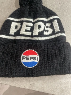 Svart Pepsi mössa med tofs - Säljer denna mössa den är aldrig använd 