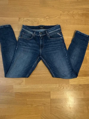 Blå slim fit jeans från Replay - Snygga blå slim fit jeans från Replay med klassisk femficksdesign och diskreta slitningar. Jeansen har normal midja, Jeansen är i storlek 14A replay jeansen är knappt använda 