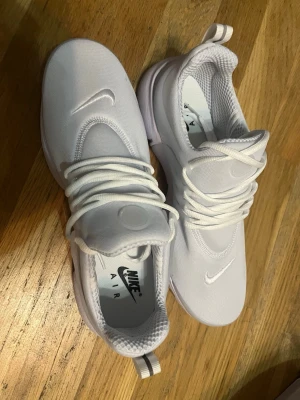 Nike Air presto - Fräscha helvita Nike Air sneakers med klassisk låg siluett. Skorna har en stilren design med diskreta swoosh-loggor och tjocka vita snören. Ovandelen är i mesh och syntet för en luftig känsla och bekväm passform. Perfekta för dig som gillar en clean och sportig look.