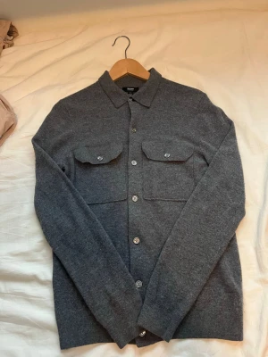 Grå overshirt från Reiss - Stilren grå overshirt från Reiss i 100% marinull. Klassisk rak passform med två bröstfickor med knappar framtill. Perfekt lager-på-lager-plagg med snygga detaljer och krage. Nypris 1500kr 