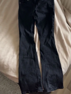 Svarta bootcut jeans - Säljer ett par svarta bootcut jeans med klassisk femficksdesign och normal midja. Jeansen har en lätt utsvängd passform nedtill och är tillverkade i ett mjukt denimtyg. Perfekta för dig som gillar en tidlös och avslappnad stil.