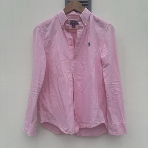 Polo Ralph Lauren skjorta  - Tjena! Rosa skjorta från Polo Ralph Lauren. Sitter alldeles för litet på modellen - 185cm lång. (Size: 14/16 - XS)  (Skick: 3/5)  (Retail: 1499kr)  (Vårt pris: 300kr). Hör av er vid frågor & funderingar. /Mvh, WC Archive.