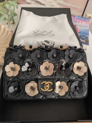 ChaneI 💎 Camellia Flap Bag. - Denna exklusiva axelremsväska är ett sant mästerverk av tredimensionell design. Den kombinerar klassisk elegans med en lekfull, feminin touch som förvandlar varje outfit till något alldeles extra.Detta är väskan för dig som älskar det unika. Den är sofistikerad nog för formella tillfällen, men tillräckligt karaktärsfull för att ge din vardagsstil en touch av lyxig romantik.