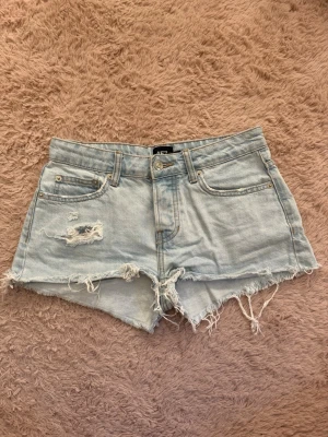 Jeansshorts  - Säljer ett par ljusblå jeansshorts från lager 157 med råa kanter och slitningar framtill. Hyfsat lågmidjade och är i storlek XS. De är tyvärr för små för mig så därför jag säljer vidare🌸