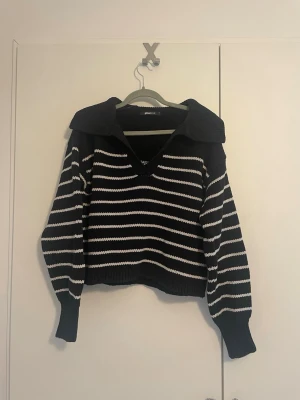Randig stickad tröja - Snygg stickad tröja från GINA TRICOT med marinblå och vita ränder. Tröjan har en bred krage, v-ringning och långa ärmar med ribbade muddar.