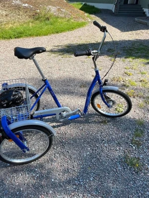 Blå trehjuling från Monark - Säljer en klassisk blå trehjuling från Monark med metallkorg bak och kromade skärmar. Cykeln har stabil ram, svart sadel och handtag samt vita detaljer på hjulen. Perfekt för dig som vill ha en unik och stadig cykel.