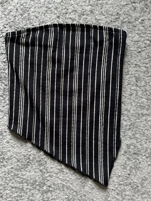 Svartvit randig bandeau tubtopp - Snygg svart tubtopp med beiga vertikala ränder. Toppen har bandeau-modell och är tillverkad i ett reflat, stretchigt material som sitter bekvämt. Perfekt för att skapa en trendig och stilren look.