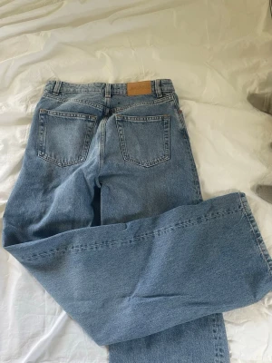Blå raka jeans från Monki - Säljer ett par klassiska blå jeans från Monki med rak passform och hög midja. Jeansen har fem fickor, bälteshällor och stängs med knapp och dragkedja. Tillverkade i slitstark denim som ger en tidlös look.