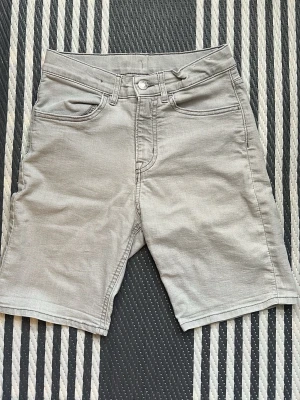 Grå slim fit denimshorts - Snygga grå denimshorts från &Denim i slim fit-modell. Klassisk femficksdesign med knapp och dragkedja framtill. Perfekta för en avslappnad och trendig look under varma dagar. Storlek 152.