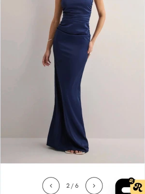 Marinblå långklänning i satin - Elegant marinblå långklänning i glansigt satinmaterial med figurnära passform. Klänningen har smala axelband, öppen rygg och en lätt draperad effekt över midjan. Perfekt för speciella tillfällen där du vill sticka ut. Är storlek s men insydd i midjan så passar xs men enkelt att sprätta upp även uppsydd så passar en som är typ 175 o kortare såklart. Använd 1 gång så väldigt bra skick! 