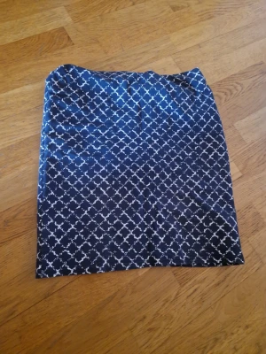 Mönstrad blå kjol från KappAhl - Snygg blå kjol från KappAhl med vitt rutigt mönster. Kjolen har rak passform och är i mjukt material som känns bekvämt. Perfekt att matcha med en enkel topp för en stilren look.