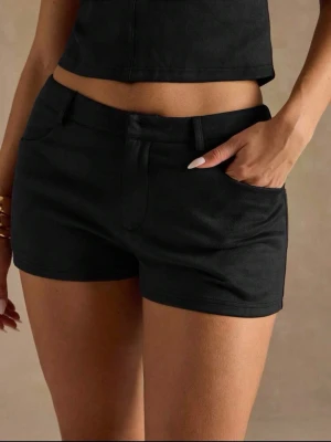 Svarta lågmidjade kostymshorts - Snygga svarta kostymshorts med lågmidja och klassisk design. De har bälteshällor och stängs med dragkedja och knapp. Materialet känns mjukt och är troligtvis bomull eller en bomullsblandning. Perfekta till sommarens alla outfits. Storlek M men passar både S/M! Helt nya!