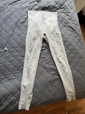 Ljusgrå sömlösa leggings - Snygga ljusgrå leggings med hög midja och sömlös design. De är stretchiga och sitter tajt längs benen, perfekta för en sportig och trendig look. Materialet känns mjukt och följsamt mot huden.