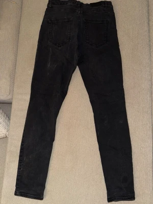 Svarta skinny jeans - Säljer ett par svarta skinny jeans med klassisk femficksdesign och smal passform. Jeansen har normal midja och är tillverkade i stretchigt denimtyg för extra komfort. Perfekta för en avslappnad och trendig stil.