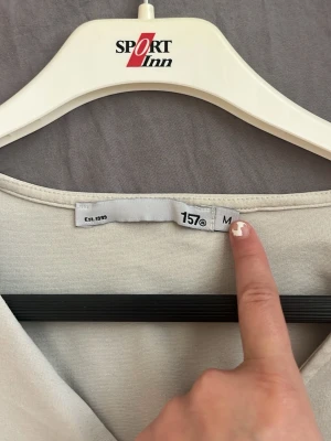 Vit v-ringad topp med knappar 157 - Säljer en stilren vit topp från 157 med v-ringning och tre dekorativa knappar framtill. Toppen har korta ärmar och är gjord i mjukt bomullsmaterial, perfekt för en enkel och clean look.