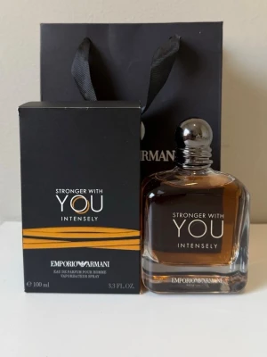Emporio Armani Stronger With You Intensely - Emporio Armani Stronger With You Intensely är en herrparfym med en elegant, fyrkantig glasflaska och silverfärgad rund kork. Doften kommer i en svart kartong med orange detaljer och tydlig logga. Flaskan rymmer 100 ml och har en varm bärnstensfärgad vätska.
