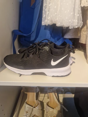 Svarta Nike sneakers med vit sula - Snygga svarta Nike sneakers med vit sula och klassisk vit swoosh på sidan. Ovandelen är i meshmaterial för bra andningsförmåga och skorna har svarta snören. Perfekta för en sportig och avslappnad stil.