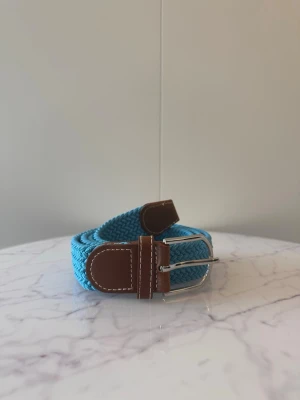 Blått flätat bälte - Tja säljer helt nya svenska klassiska flätade bälten från Bältgallerian i storlek 105cm lång och 3,5cm bred. Dem är i ett elastiskt material och finns i flera olika färger i min profil