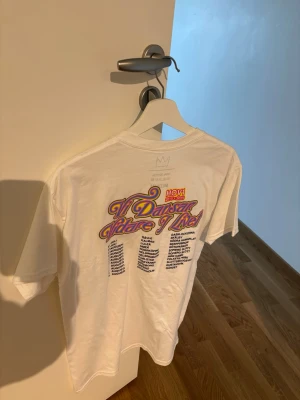 Hov1 T-shirt - Säljer en vit t-shirt från Hov1 med trycket 'Vi Dansar vidare i livet”  på ryggen och en liten krona på bröstet. T-shirten har rund hals, korta ärmar och är gjord i mjuk bomull. Perfekt för dig som gillar svensk musik och stilrena plagg. Aldrig använd 