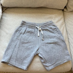 Grå mjukisshorts från H&M Divided XS - Gråa mjukisshorts med elastisk midja och vit snörning. Två fickor fram och en bakficka.