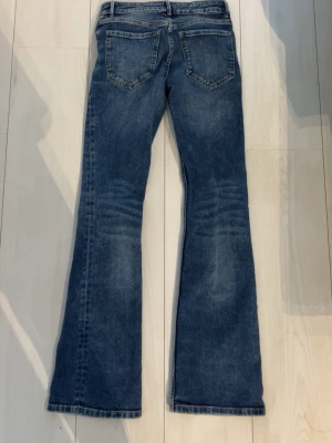 Blå bootcut jeans med utsvängda ben - Snygga blå bootcut jeans med klassisk femficksdesign och utsvängda ben. Jeansen har normalhög midja och är tillverkade i denim med lätt tvättad look. Perfekta för dig som gillar en retrostil och vill ha ett par jeans som sticker ut.