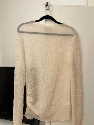 Beige transparent topp från Zara - Säljer en beige, transparent långärmad topp från Zara. Toppen har en crinklad struktur och är lätt och luftig, perfekt för lager på lager. Enkel och stilren design utan synliga detaljer eller mönster. Passar dig som gillar minimalistisk och trendig stil.