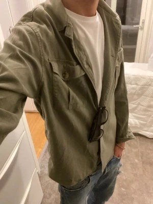 overshirt från bondelid - Olivgrön overshirt från Bondelid i storlek S. Skjortan har två bröstfickor med knappar, klassisk krage och knäppning framtill. Tillverkad i ett mjukt linnematerial som ger en chill och avslappnad vibe. Perfekt att slänga över en t-shirt för en cool look.