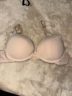 Ljusbeige push-up bh - Ljusbeige push-up bh med släta kupor och justerbara axelband i satin. Bh:n har bygel och klassisk knäppning bak. Perfekt för en diskret look under ljusa kläder. 70B 