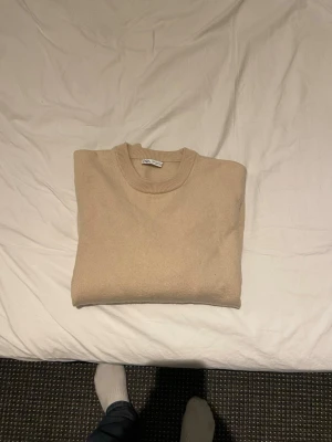 Beige tröja från Zara Man - En stilren beige tröja från Zara Man med rund halsringning och ribbade muddar vid ärmslut och nederkant. Perfekt för lager-på-lager och enkel att matcha med olika outfits. Mjuk och skön känsla, passar dig som gillar minimalistisk stil.