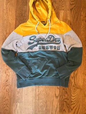 Superdry hoodie - En snygg superdry hoodie med unika färger. Bra skick men små hål vid slutet av armarna. Skriv om du har frågor