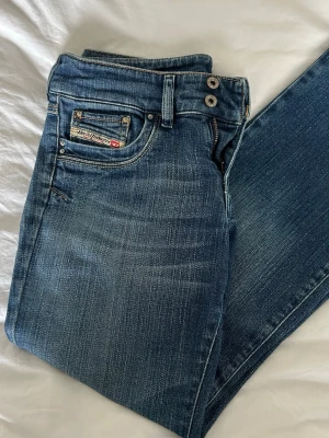 Blå diesel jeans - Snygga blå low waist bootcut jeans från Diesel med klassisk femficksmodell. Jeansen har en stilren look och detaljerade sömmar samt ett diesel industry märke på myntfickan. Perfekta för en snygg och trendig stil men passar tyvärr inte mig längre. Skriv för fler bilder!