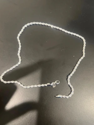 Silverfärgat tvinnat halsband - Snyggt halsband i silverfärg med tvinnad kedja som ger en stilren och modern look. Halsbandet har en enkel karbinhake och passar perfekt till olika stilar. Materialet ser ut att vara metall med blank finish.