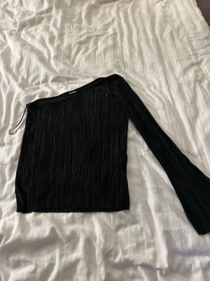 Svart oneshoulder topp Gina Tricot - Säljer en svart oneshoulder topp från Gina Tricot med ribbad struktur.