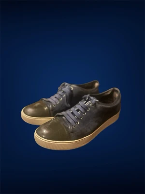 Mörkblå Lanvin sneakers med cap toe  - Snygga mörkblå Lanvin sneakers med tåparti i blankt material och matchande blå skosnören. Skorna har en vit sula med diskret mönster och klassisk låg profil. Perfekta för en avslappnad streetstyle-look men även fina middagar och vanliga sommardagar!