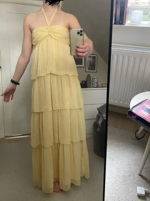 Ljusgul långklänning med volanger - Perfekt som balklänning! Helt oanvänd, prislapps kvar. Är ca 170cm 