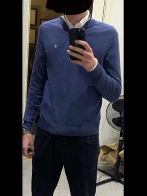 Blå halvzip tröja från Morris - Snygg blå stickad tröja från Morris med halv dragkedja och kontrastfärgad insida på kragen. Tillverkad i 100% merinoull och har en liten broderad logga på bröstet. Perfekt för lager på lager och riktigt skön att bära.