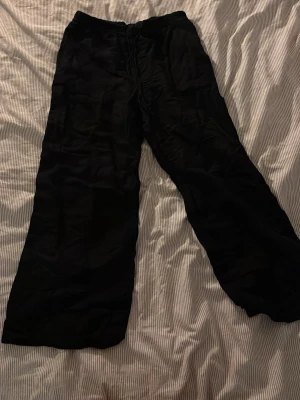 Svarta linnebyxor från H&M - Säljer ett par svarta linnebyxor från H&M med avslappnad passform och raka ben. Byxorna har dragsko i midjan för extra komfort och är tillverkade i ett lätt och luftigt material som passar perfekt till sommaren.