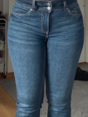 Blå boot cat  jeans med dekorficka - Snygga blå skinny jeans med hög midja och dekorativ knappdetalj på bakfickan. Klassisk femficksmodell med kontrastsömmar och dragkedjegylf. Aldrig använda