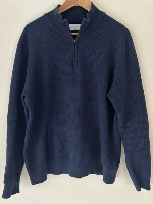 Mörkblå halvzip-tröja från Volt  - Mörkblå stickad tröja från Morris med halvzip och hög krage. Tröjan har en klassisk, rak passform och ribbade muddar vid ärmslut och nederkant. Perfekt för lager-på-lager och funkar till både jeans och chinos. Nypris var 899kr, säljer den för 400kr 