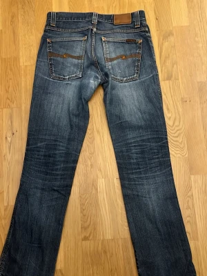 Blå vintage jeans från nudie 31/32  - Säljer nu mina nudiejeans då de ej passar! 🙂Modellen heter Slim Jim och den tillverkas inte längre. Dry Broken Twill, 100% Bomull. Slitna men i bra sick - inga hål! Skriv om ni har några funderingar.🙌
