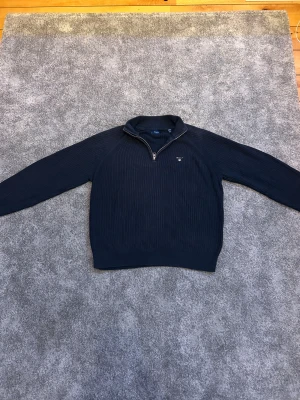 Stickad GANT tröja - Säljer denna sjukt snygga mörkblå stickad tröja från Gant med halfzip. Klassisk och stilren design som passar till det mesta. Storlek är 170 cm och rekommenderas för 15 års ålder. Använd en hel del och har lätt slitet material. Vid fler frågor eller funderingar så är det bara att kontakta oss! Mvh // JJ Studios
